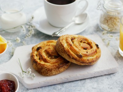 Breakfast 3 About Homey Served delicious breakfast meal with baked buns on wooden board on marble table with coffee and juice and jam