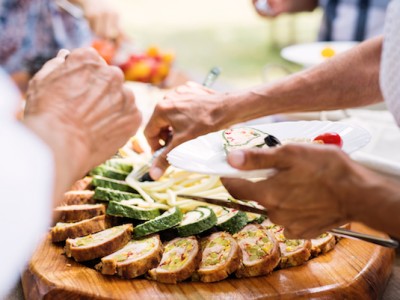 food 2 2 About Homey Close-up of unrecognizable people putting food on their plates. Family celebration outside in the backyard. Big garden party.